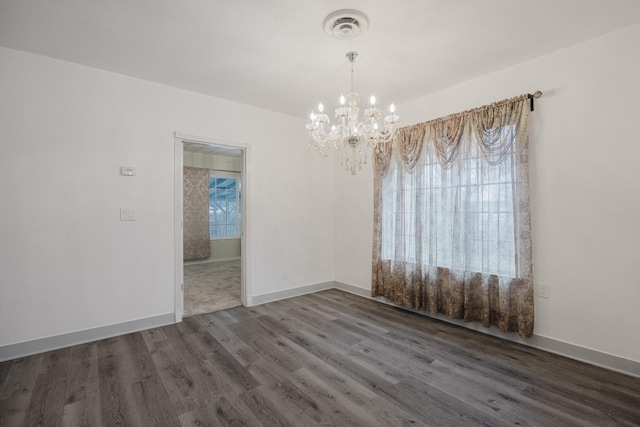 empty room featuring baseboards, plenty of natural light, visible vents, and wood finished floors