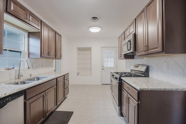 kitchen featuring baseboards, visible vents, light stone countertops, stainless steel appliances, and a sink