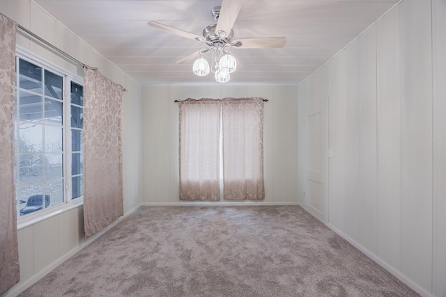 carpeted spare room with a decorative wall, a wealth of natural light, and a ceiling fan