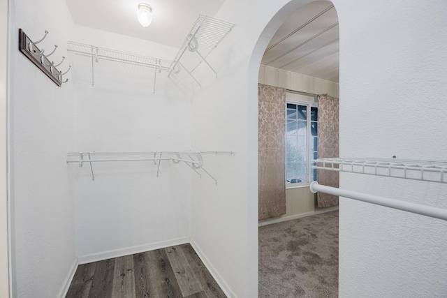 spacious closet with arched walkways and wood finished floors