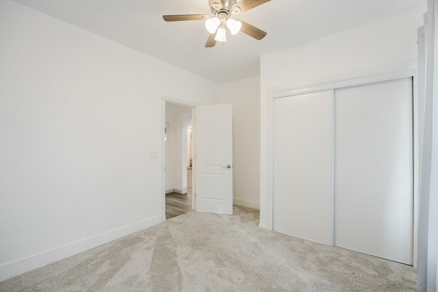 unfurnished bedroom with carpet floors, a ceiling fan, baseboards, and a closet