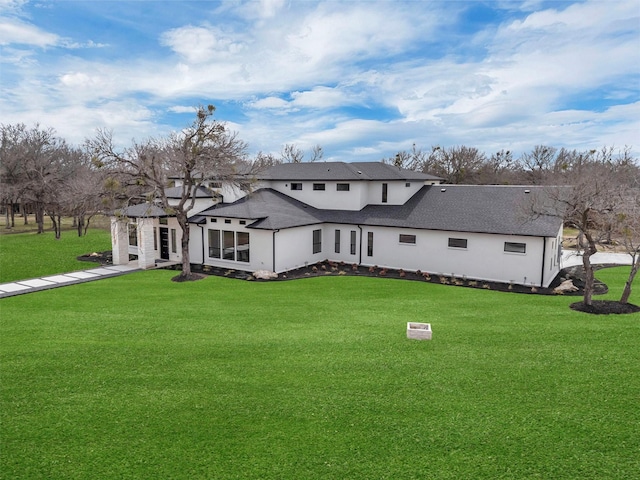 back of property featuring a shingled roof and a yard