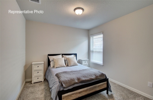 bedroom with carpet flooring, visible vents, baseboards, and a textured ceiling