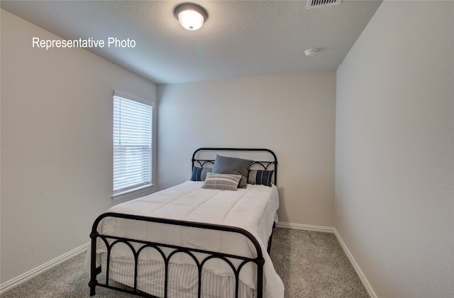 bedroom with a textured ceiling, carpet floors, and baseboards