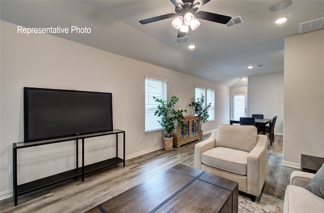 living room with baseboards, visible vents, vaulted ceiling, and wood finished floors