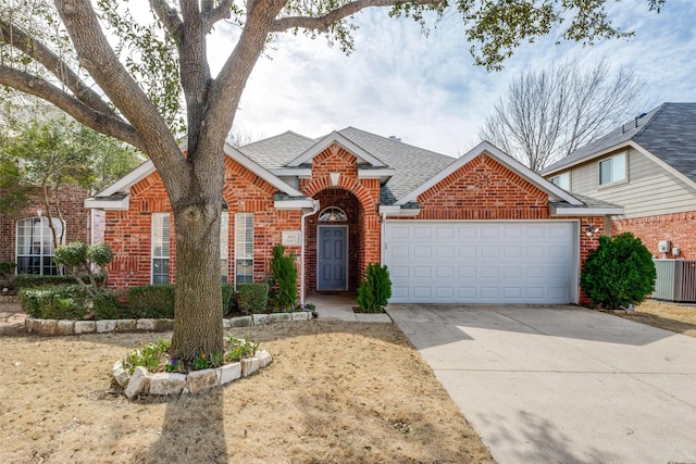 traditional home with driveway, a garage, a shingled roof, central AC unit, and brick siding