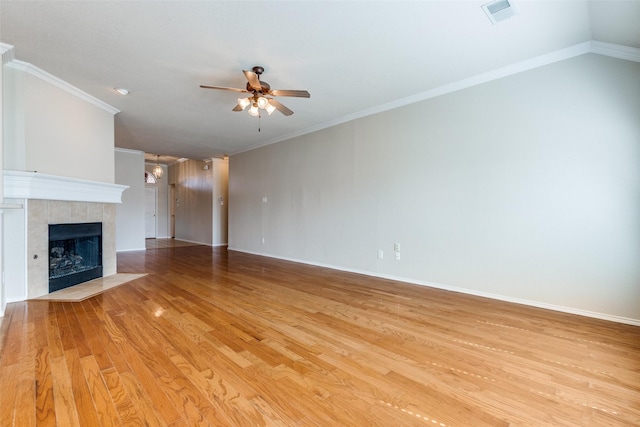 unfurnished living room with light wood-style flooring, a tiled fireplace, visible vents, and crown molding