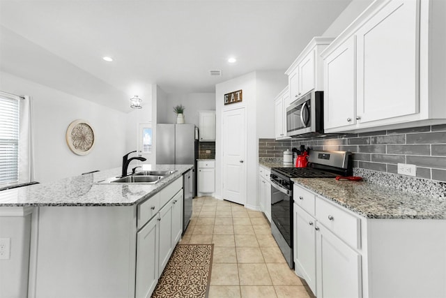 kitchen with visible vents, decorative backsplash, appliances with stainless steel finishes, a kitchen island with sink, and a sink