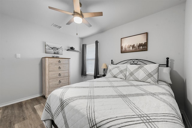 bedroom with baseboards, visible vents, ceiling fan, and wood finished floors