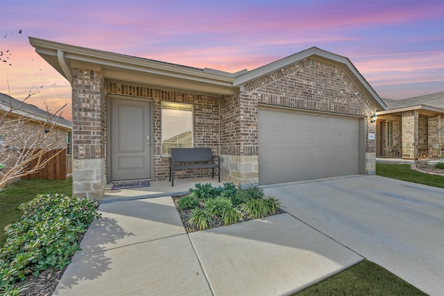 single story home featuring an attached garage, stone siding, driveway, and brick siding