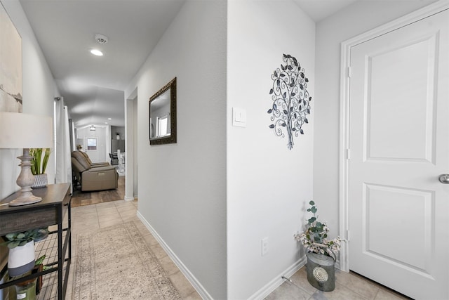 corridor with baseboards and light tile patterned floors