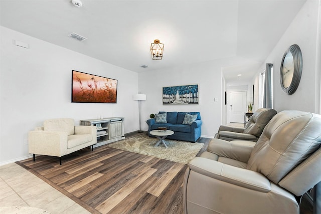 living area featuring an inviting chandelier, baseboards, visible vents, and wood finished floors