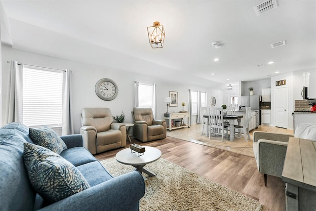 living room featuring light wood-style floors, visible vents, and recessed lighting