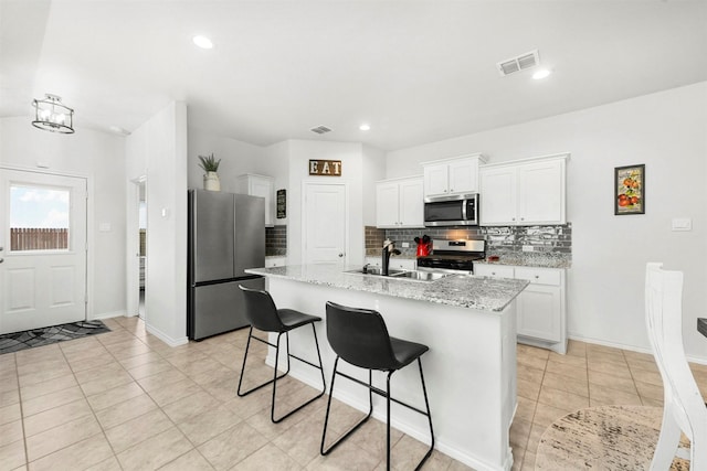 kitchen featuring tasteful backsplash, visible vents, white cabinets, appliances with stainless steel finishes, and a sink