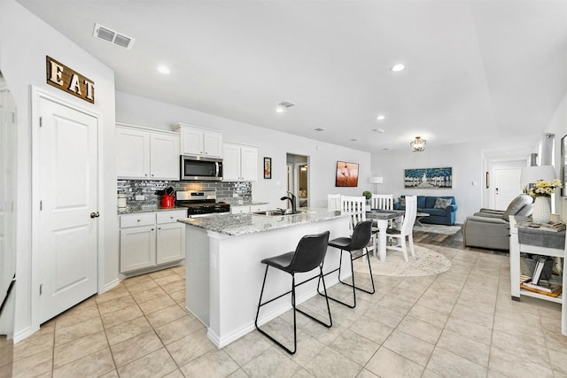 kitchen with a sink, visible vents, white cabinets, appliances with stainless steel finishes, and decorative backsplash