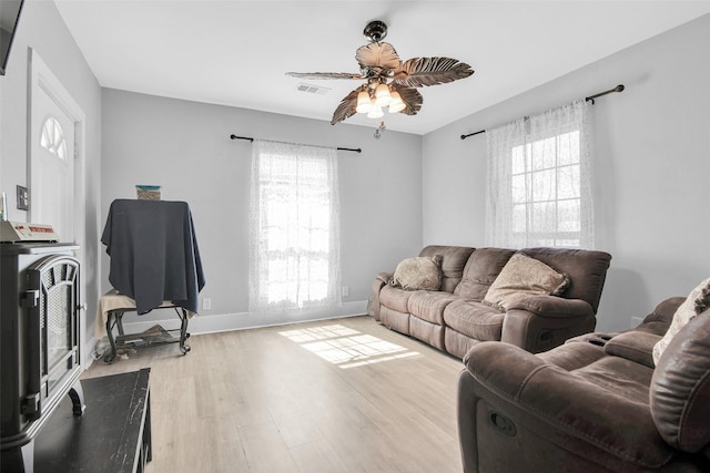 living area with a ceiling fan, visible vents, plenty of natural light, and wood finished floors