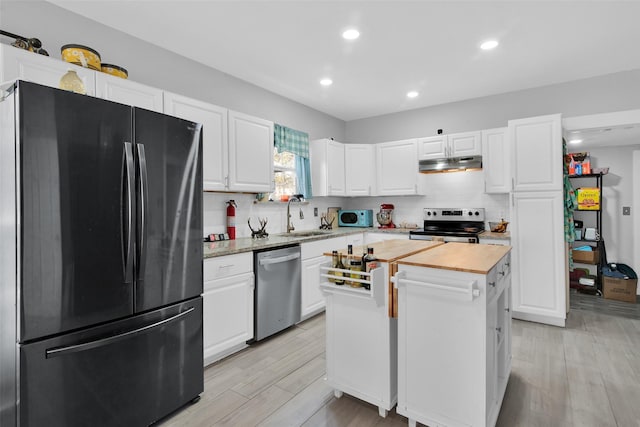 kitchen with white cabinets, a sink, stainless steel appliances, under cabinet range hood, and backsplash