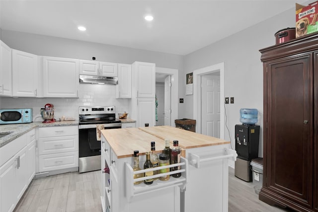 kitchen with stainless steel electric stove, tasteful backsplash, white microwave, butcher block countertops, and under cabinet range hood