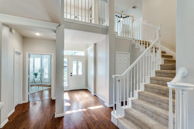 foyer with a towering ceiling, visible vents, baseboards, and wood finished floors