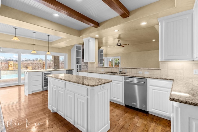 kitchen featuring wine cooler, a kitchen island, a peninsula, stainless steel dishwasher, and a sink