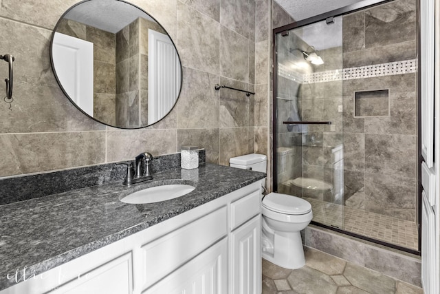 bathroom featuring toilet, tile walls, a shower stall, and vanity