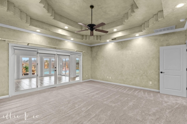 carpeted spare room with a ceiling fan, visible vents, baseboards, french doors, and a tray ceiling