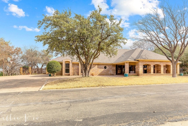 view of front facade featuring a shingled roof, concrete driveway, and brick siding