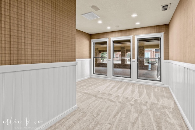 carpeted spare room with recessed lighting, visible vents, wainscoting, a textured ceiling, and wallpapered walls