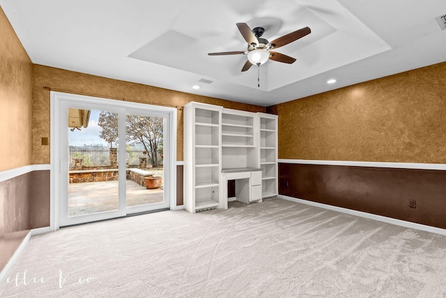 empty room featuring carpet floors, a tray ceiling, visible vents, and wallpapered walls