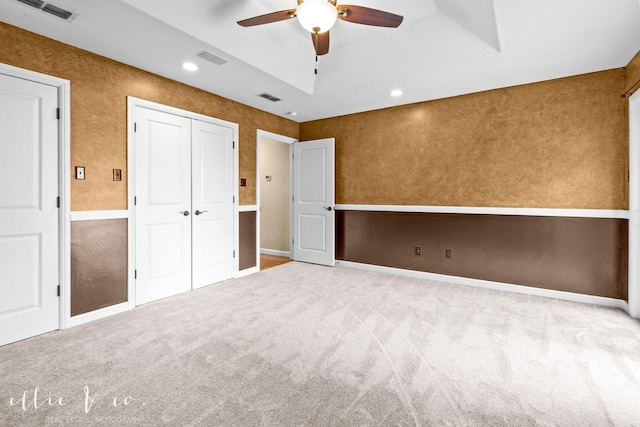 unfurnished bedroom with carpet floors, visible vents, a tray ceiling, and recessed lighting