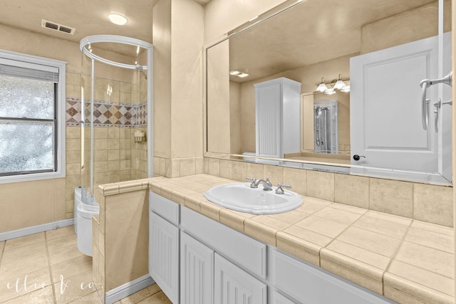 full bathroom with tile patterned flooring, vanity, visible vents, baseboards, and tiled shower