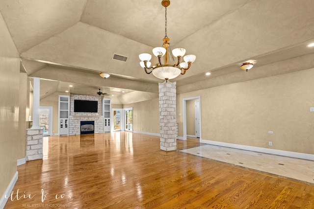 unfurnished living room with a fireplace, wood finished floors, visible vents, baseboards, and decorative columns