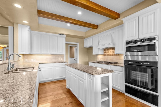 kitchen with light wood-style flooring, double oven, premium range hood, a sink, and a warming drawer