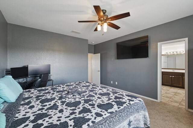 bedroom with visible vents, ensuite bathroom, a ceiling fan, baseboards, and light colored carpet