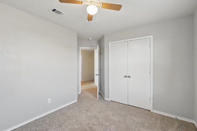 unfurnished bedroom with visible vents, baseboards, light carpet, a closet, and a ceiling fan