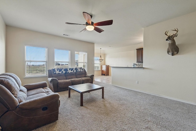 living area featuring visible vents, light colored carpet, baseboards, and a ceiling fan