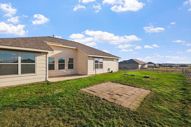 back of property with a yard, a patio, a shingled roof, and fence