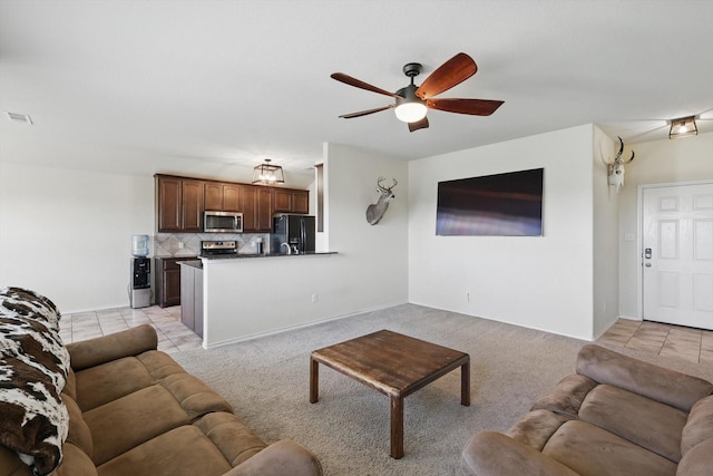 living room featuring light tile patterned floors, light colored carpet, and a ceiling fan