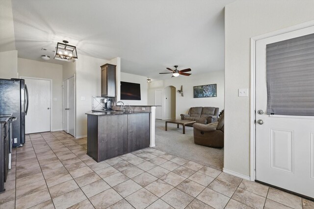 kitchen featuring a sink, open floor plan, freestanding refrigerator, arched walkways, and ceiling fan