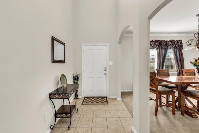 entryway featuring arched walkways, baseboards, and light tile patterned floors