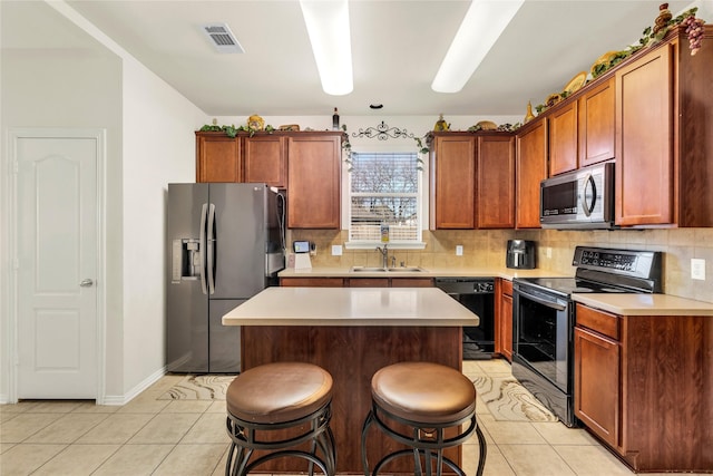 kitchen featuring light tile patterned floors, a breakfast bar area, a sink, appliances with stainless steel finishes, and decorative backsplash