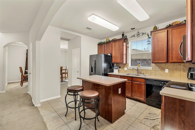 kitchen featuring arched walkways, a breakfast bar area, visible vents, appliances with stainless steel finishes, and a sink