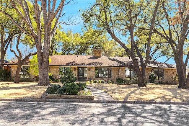 view of front of home with brick siding, a chimney, and french doors