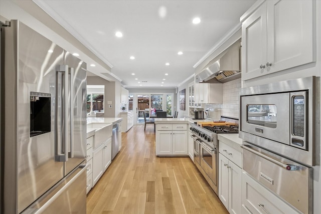 kitchen featuring a peninsula, crown molding, stainless steel appliances, and light countertops