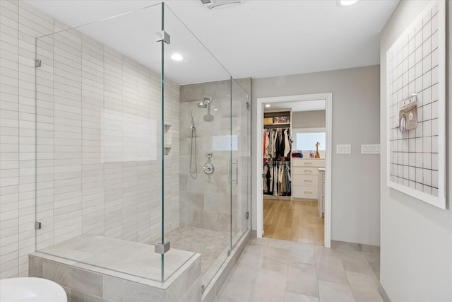 bathroom with baseboards, tile patterned floors, a spacious closet, a shower stall, and recessed lighting