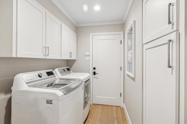 clothes washing area featuring crown molding, cabinet space, light wood-style flooring, washing machine and dryer, and baseboards