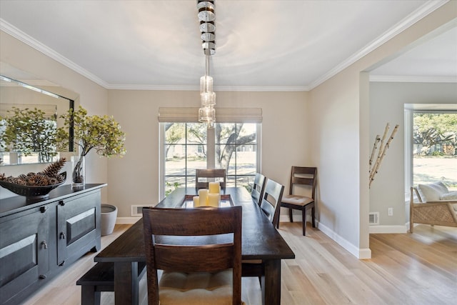 dining room featuring visible vents, ornamental molding, light wood-style flooring, and baseboards