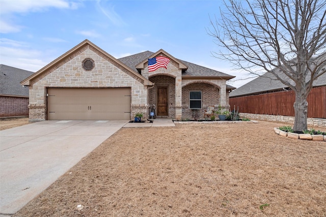 french provincial home featuring brick siding, a shingled roof, concrete driveway, fence, and a garage