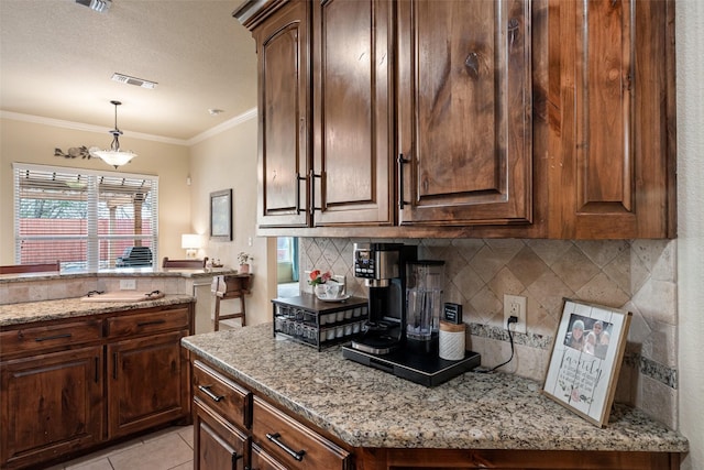 kitchen featuring light tile patterned flooring, light stone countertops, visible vents, and crown molding