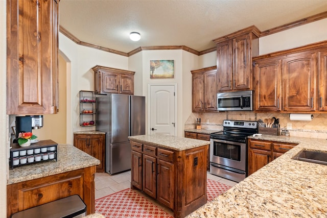 kitchen featuring light tile patterned floors, light stone counters, appliances with stainless steel finishes, ornamental molding, and backsplash